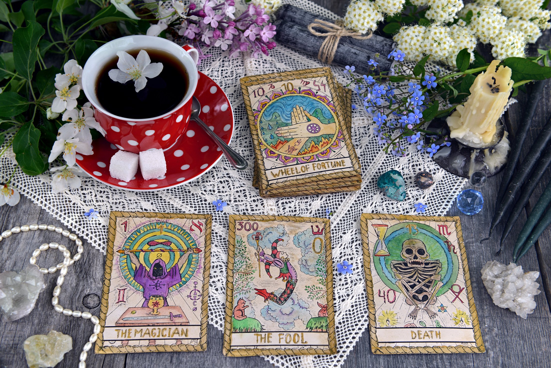 Tarot cards with cup of tea, flowers and black candles on planks